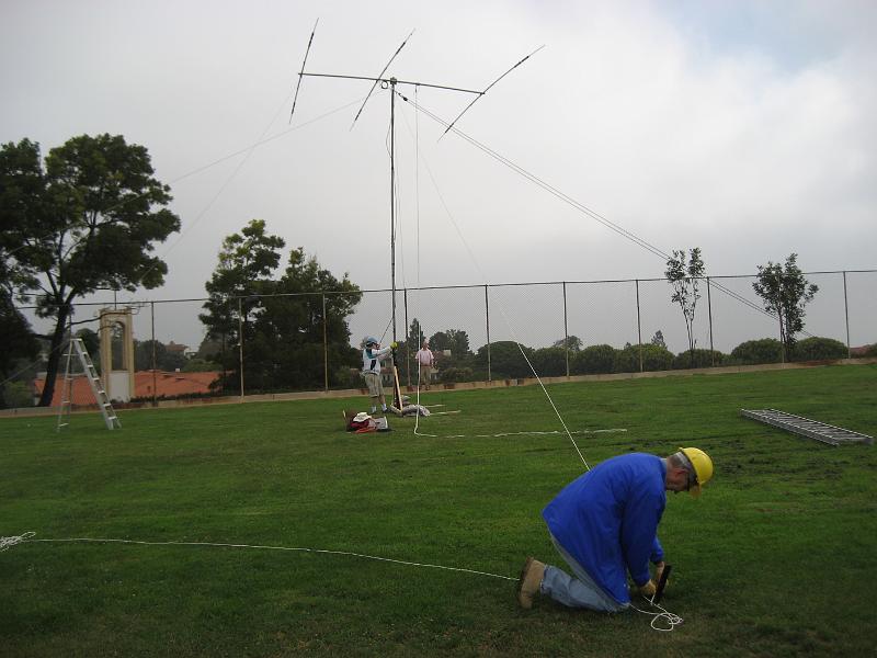 IMG_1013.JPG - Bob Closson W6HIP at stake. Clay Davis AB9A holding the mast.  Dale Hanks N6NNW at the fence.