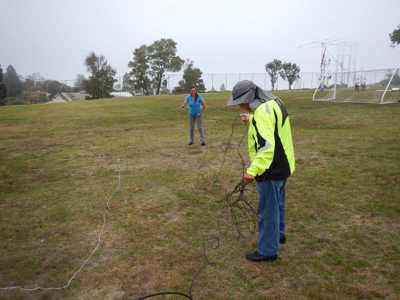 038a.jpg - Laura, KK6BFI, and Jim, KK6MNT, untangle the 80-meter wire dipole going onto the tower trailer.