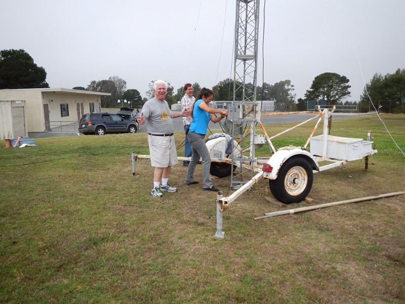 050a.jpg - Laura, KK6BFI, cranks up the tower as Walt, K1DFO, and Rocco, N6KN, observe.